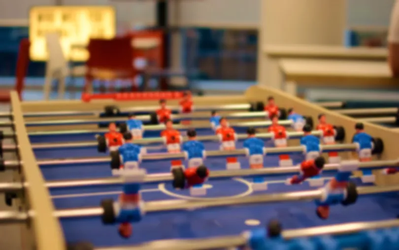 Close-up van een tafelvoetbalspel met rode en blauwe poppetjes op kantoor